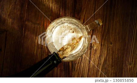 Pouring Beer into Pint Glass on Old Wooden Table, Top Down View. 130855850