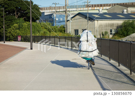夏の朝の住宅地を渡る自転車を乗るホームレスの方の様子 130856070