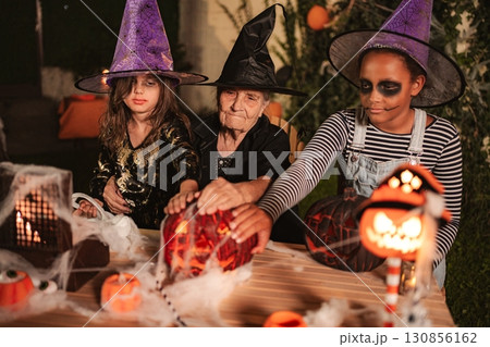 Family celebrating Halloween together, touching a carved pumpkin 130856162