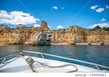 View of idyllic Algarve coast cliffs caves beaches with people blue sky from boat View of idyllic Algarve coast cliffs caves beaches with people blue sky from boat 130856661