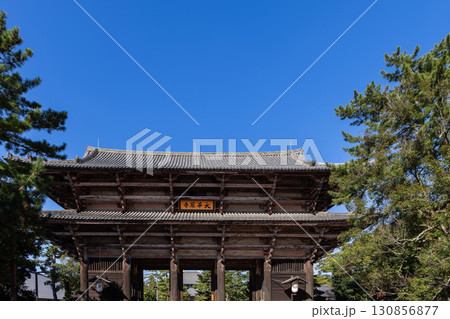 Grand South Gate of Todai ji Temple Nara Japan framed by autumn trees and blue sky in frontal view 130856877
