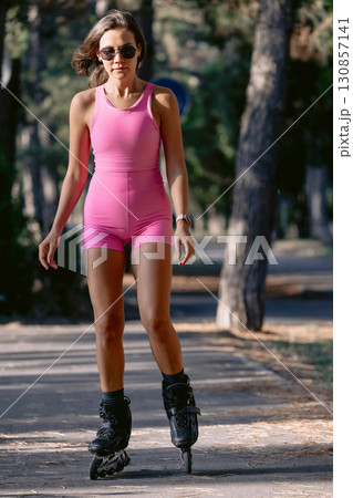 Woman in pink sportswear rollerblading in the park on a sunny day, active fitness concept. 130857141