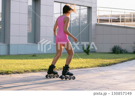 Sexy woman in pink sportswear rollerblading outdoors on a sunny day, active lifestyle and fitness concept. Sexy woman in pink sportswear rollerblading outdoors on a sunny day, active lifestyle and fitness concept. 130857149