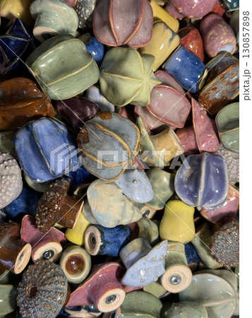 Assorted colorful ceramic pottery beads displayed in a pile, ideal for crafting or decor background 130857898