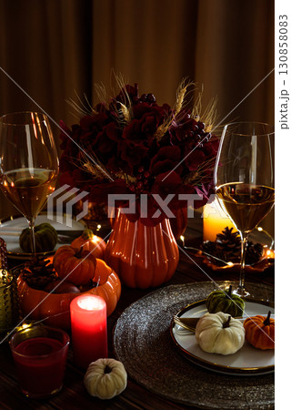 Thanksgiving table setting with decorative pumpkins, candles and string lights on dark wooden table Thanksgiving table setting with decorative pumpkins, candles and string lights on dark wooden table 130858083