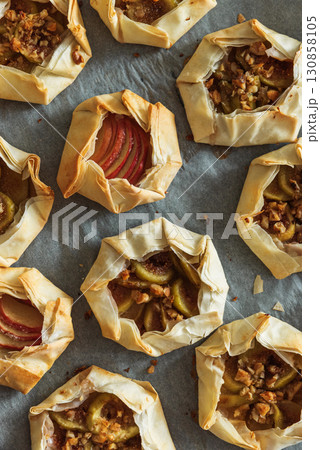 Mini Fig and Apple Galettes with Nuts on Parchment Background Mini Fig and Apple Galettes with Nuts on Parchment Background 130858105