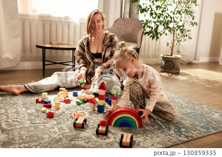 Mother and child playing with educational toys on a carpet in a cozy room 130859335