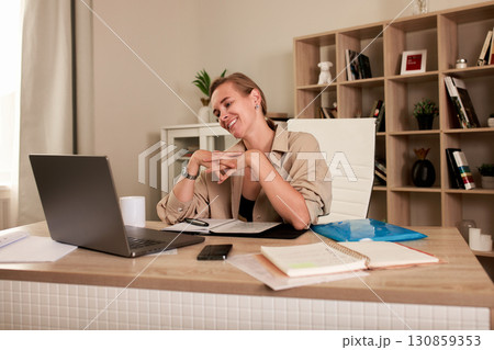 Smiling woman engaging in virtual meeting from a modern home office Smiling woman engaging in virtual meeting from a modern home office 130859353