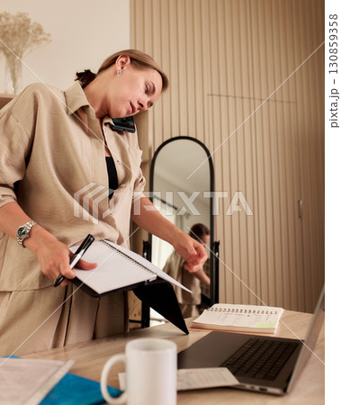 Professional multitasking at a home office workspace with notebooks and laptop 130859358