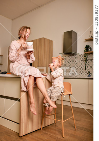 Mother and daughter enjoying a warm drink together in the kitchen Mother and daughter enjoying a warm drink together in the kitchen 130859377