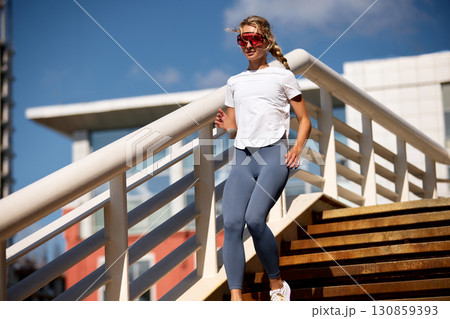 Athletic woman jogging on a sunny day wearing stylish fitness outfit Athletic woman jogging on a sunny day wearing stylish fitness outfit 130859393