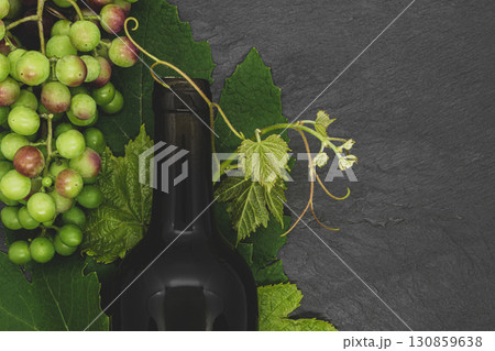 Wine bottle and young grape twig with leaves and unripe grapes 130859638