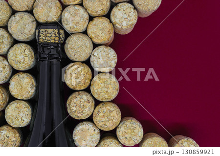 Black champagne bottle surrounded of many champagne corks 130859921