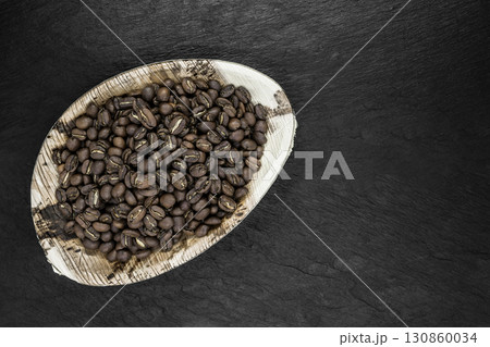 Bunch of Coffee Beans in Natural Banana Leaf Plate on Black Stone Background Surface 130860034
