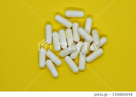 Bunch of white medication pills on yellow background surface 130860048