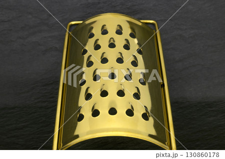 Golden grater on black stone background 130860178
