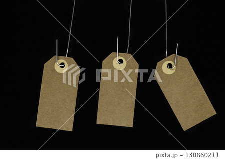 Hanging blank brown note cards with copy space hooked on metal spring and isolated on black background 130860211