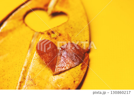 Heart shape made from leaf on yellow background 130860217