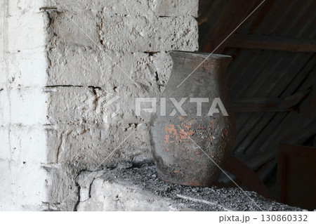 Old, Rustic and Dusty Brown Vase Standing Near White Brick Wall 130860332