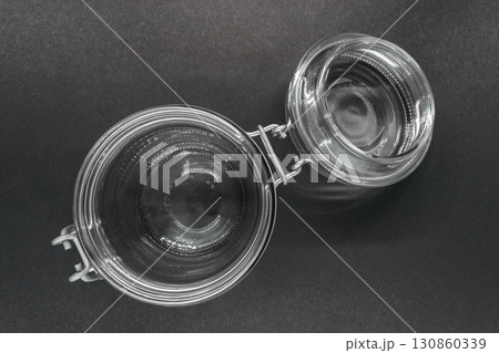 Open glass jar with metal holder on black background surface 130860339