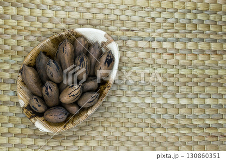 Pecan Nuts with the Nutshell in Eco Natural Banana Leaf Plate on Natural Bamboo Mat Surface with Free Space Pecan Nuts with the Nutshell in Eco Natural Banana Leaf Plate on Natural Bamboo Mat Surface with Free Space 130860351