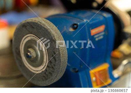 Grinding wheel spinning on bench grinder in workshop Grinding wheel spinning on bench grinder in workshop 130860657