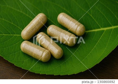 Herbal supplement capsules placed on fresh green leaf natural medicine photography organic wellness product 130860892