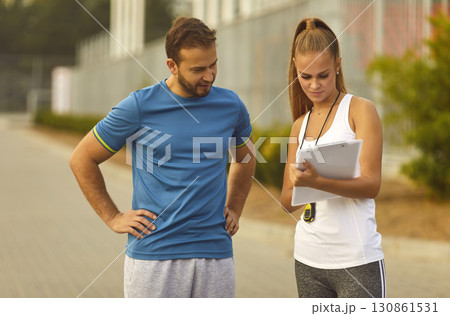 Couple watching the results of sports training outdoors checking time for performance in park. 130861531