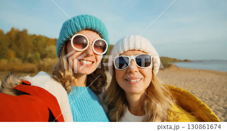 Happy young two women friends taking selfie with phone on beach, smiling girlfriends having fun 130861674
