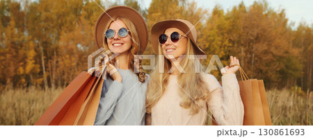 Fashionable happy two women friends with shopping bags, stylish smiling girlfriends in autumn park 130861693