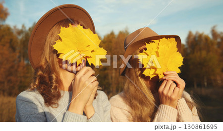 Happy two women friends with autumn yellow leaves, funny girlfriends having fun together in park 130861695