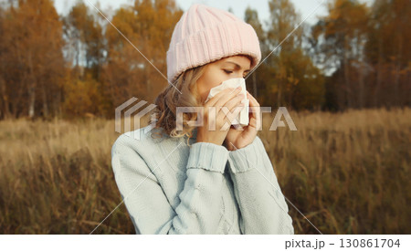 Sick woman sneezing blow nose using tissue, unhealthy suffering girl feels unwell outdoors Sick woman sneezing blow nose using tissue, unhealthy suffering girl feels unwell outdoors 130861704