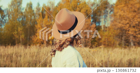 Beautiful woman in hat enjoying warm weather in autumn park with yellow leaves, nature background Beautiful woman in hat enjoying warm weather in autumn park with yellow leaves, nature background 130861732