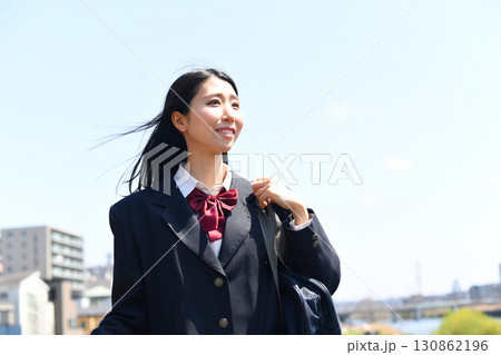 日本の女子高生が青空の下で笑顔で通学する 日本の女子高生が青空の下で笑顔で通学する 130862196