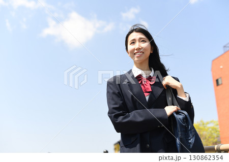 日本の女子高生が青空の下で笑顔で通学する 日本の女子高生が青空の下で笑顔で通学する 130862354