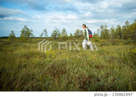 Joyful active woman forager walking after mushroom picking on raised peat bog in forest wetlands 130862897
