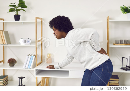 Young woman suffering from backache holding her lower back Young woman suffering from backache holding her lower back 130862939