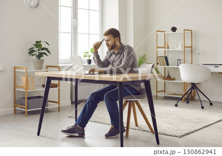 Focused bearded man working at home office with laptop computer Focused bearded man working at home office with laptop computer 130862941