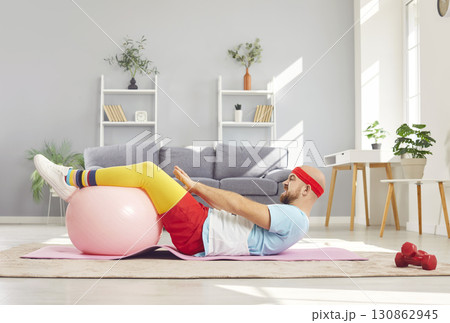 Funny young man in sportswear having home workout lying on floor on yoga mat. Funny young man in sportswear having home workout lying on floor on yoga mat. 130862945