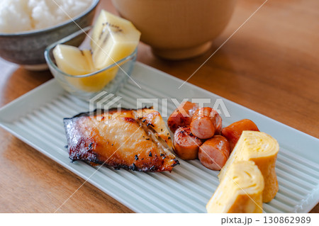 焼き魚と卵焼き、ソーセージ、キウイ、ご飯と味噌汁の和朝食 130862989