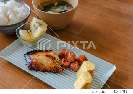 焼き魚と卵焼き、ソーセージ、キウイ、ご飯と味噌汁の和朝食 130862992