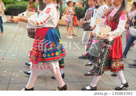 Girls in Bulgarian folk costumes walking and scattering rose petals. City parade with Bulgarian women in embroidered dresses, traditional outfits carrying baskets of roses petals Girls in Bulgarian folk costumes walking and scattering rose petals. City parade with Bulgarian women in embroidered dresses, traditional outfits carrying baskets of roses petals 130863365
