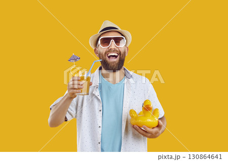 Funny bearded man in beach hat and sunglasses holding cocktail on yellow background. Funny bearded man in beach hat and sunglasses holding cocktail on yellow background. 130864641