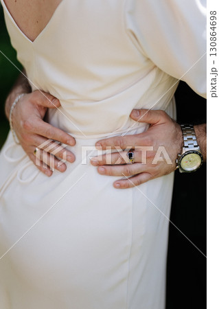 Man embracing woman in elegant dress, close up on hands with rings and luxury watch 130864698