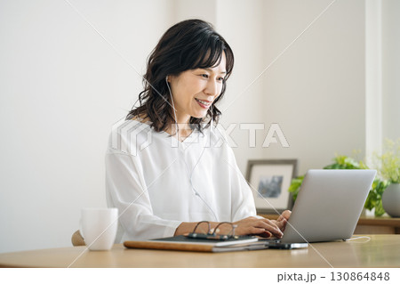 家のリビングでテレワークをするミドル女性 家のリビングでテレワークをするミドル女性 130864848