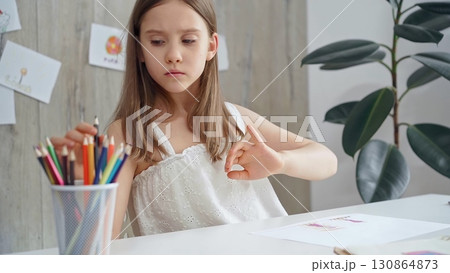 Young girl choosing colored pencils and picking a pencil from a colorful set for a creative activity Young girl choosing colored pencils and picking a pencil from a colorful set for a creative activity 130864873