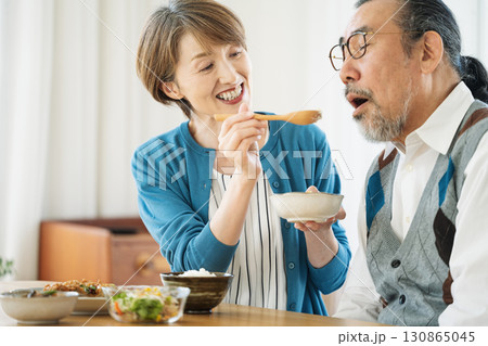 夫にご飯を食べさせるミドル女性 130865045