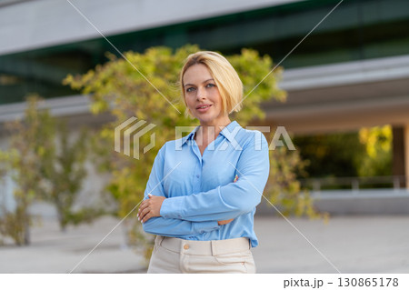 Confident young blond businesswoman standing arms Confident young blond businesswoman standing arms 130865178