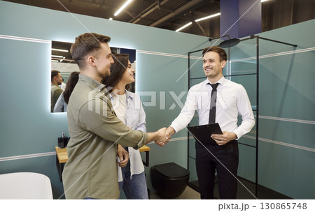 Young Couple Shakes Hands with Salesman After Successful Purchase 130865748