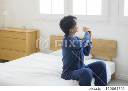 ベッドで伸びをする男性 130865891